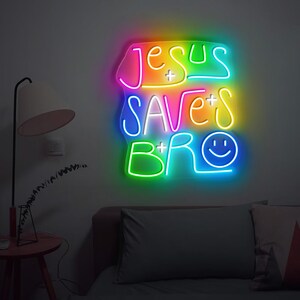 May include: A neon sign with the text "Jesus Saves Bro" in a rainbow color scheme. The sign has a smiley face at the end of the text.