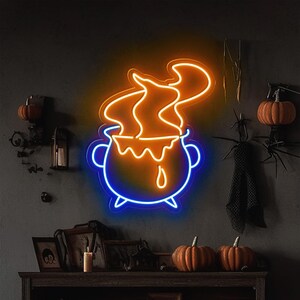 May include: A neon sign depicting a blue cauldron with orange flames and dripping orange liquid. The sign is mounted on a dark grey wall with a wooden shelf below it.