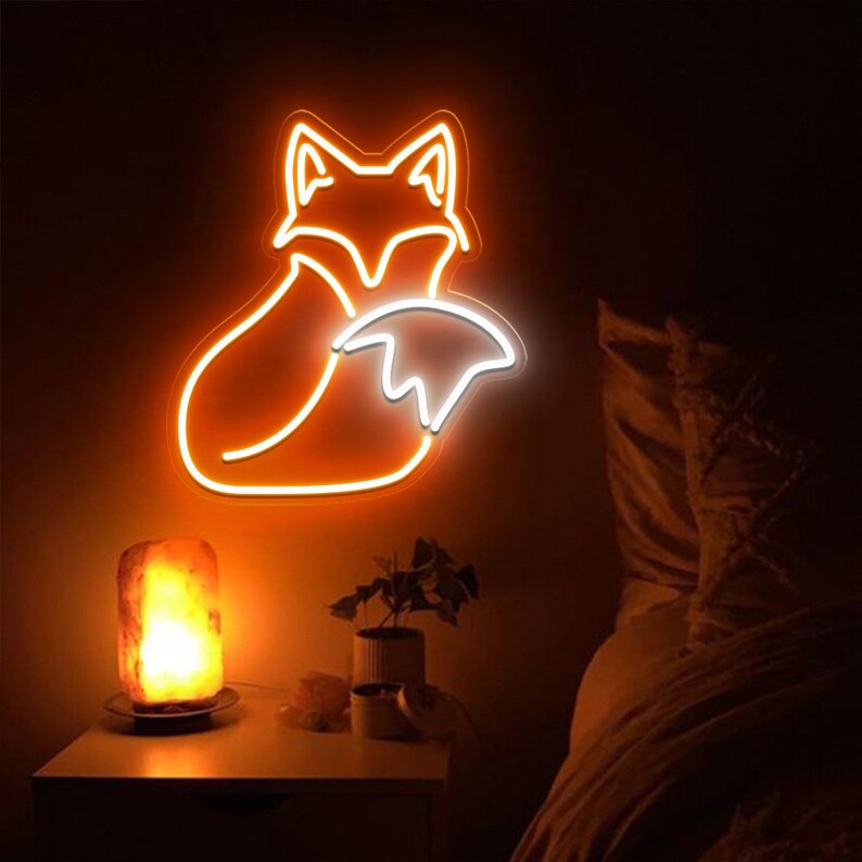 May include: A neon sign shaped like a fox with its tail curled around its body. The sign is lit up in orange and white, and is mounted on a wall in a dark room.