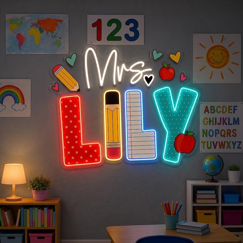 May include: A custom neon sign displaying the text Mrs. LILY in a classroom theme. The letters feature patterns including red polka dots, a yellow pencil, lined notebook paper, and teal dots, accented by a red apple and small hearts.