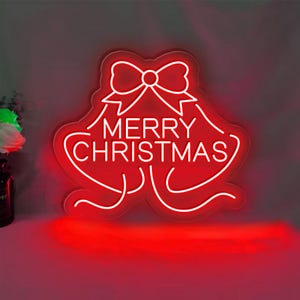 May include: White neon sign shaped like a bell with a bow on top. The sign says "Merry Christmas" in white neon letters against a red background.