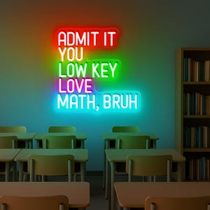 Op de afbeelding: Een neonbord met de tekst "ADMIT IT YOU LOW KEY LOVE MATH, BRUH" in rood, groen en blauw. Het bord bevindt zich in een klaslokaal met bureaus en een boekenkast vol boeken.