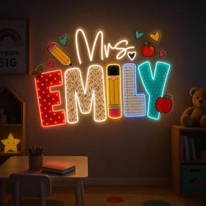 May include: A wall-mounted neon sign displaying the text Mrs. EMILY in a multi-colored, school-themed font. The letters feature patterns of polka dots, school supplies, a pencil, and lined paper, accented by small glowing hearts and red apples.