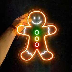 May include: A neon sign shaped like a gingerbread person with a smiling face and three colored lights on the torso. The sign is lit up and glowing.