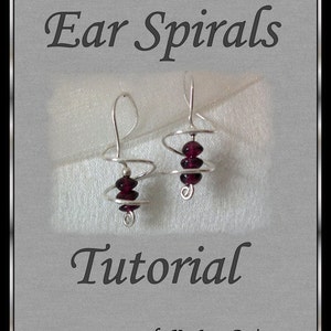 Pode incluir: Um tutorial para fazer espirais de orelha com fio e contas. A imagem mostra duas espirais de orelha prateadas com contas de cor vermelha escura. O texto "Ear Spirals Tutorial by KaeLynn Design" está na parte inferior da imagem.