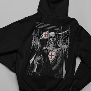 May include: Black hoodie featuring a detailed illustration of a knight on horseback, with a red cross emblem on the shield and chest. The design includes text on the back, and the knight is raising a hand in salute. The artwork has a medieval theme.