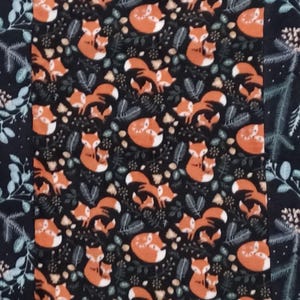 May include: A fabric with a repeating pattern of orange foxes and foliage on a black background. The foxes are in various poses, some with their young. The fabric has a forest theme and is suitable for quilting or other crafts.