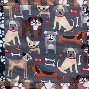 May include: A gray dog-themed fabric with various dog breeds, bones, and red balls. The fabric has a black border with white paw prints and a brown and black plaid border.