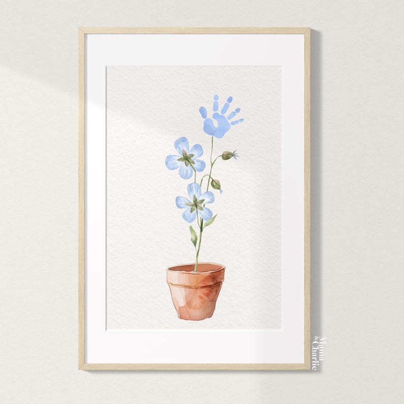 May include: A watercolor painting of a blue handprint growing into a plant with blue flowers in a terracotta pot. The painting is framed in a light wood frame.