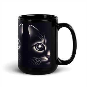 Könnte beinhalten: Schwarze Kaffeetasse mit einer weißen Illustration eines Katzenkopfes. Das Auge der Katze ist mit Sternen gefüllt.