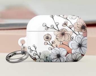 Puede incluir: Funda blanca para AirPod con diseño floral. La funda presenta un delicado patrón de flores en tonos blanco, beige y gris, con detalles de líneas negras. Un mosquetón plateado está adjunto.