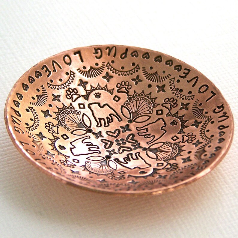 May include: A copper bowl with an intricate design etched into the surface. The design includes hearts, stars, paw prints, and the words "love you" repeated around the rim.