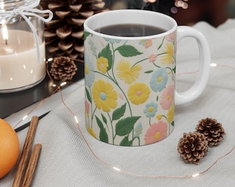 May include: A white ceramic mug with a floral pattern in shades of yellow, pink, blue, and green. The mug is filled with coffee or tea and has steam rising from it.