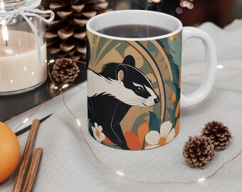 May include: A white ceramic mug with a black and white illustration of a badger on a floral background. The mug has a brown handle and is filled with a dark liquid.