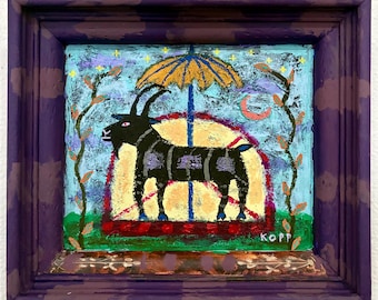 May include: A framed painting featuring a black goat standing under a yellow umbrella against a light blue background with stars and a crescent moon. The scene includes two vertical vine-like elements and the text KOPP in the bottom right corner.