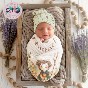 May include: A newborn baby swaddled in a white and brown swaddle with a green and brown elf illustration and the name "Michael" printed on it. The baby is wearing a green and brown hat with the name "Michael" printed on it.