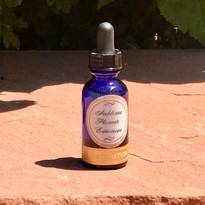 May include: A small blue glass bottle with a dropper top. The bottle has a gold label that says "Sublime Flower Essences" and "Restoration".