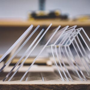 Könnte beinhalten: Eine Reihe von klaren, rechteckigen Acrylplatten, die in einer Reihe in einem Winkel aufgestellt sind. Die transparenten Paneele sind nebeneinander angeordnet und zeigen ihre glatten Kanten und gleichmäßige Dicke aus farblosem Material.