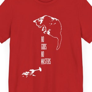 Op de afbeelding: Rood T-shirt met een wit silhouet van een kat die ondersteboven hangt met de tekst "NO GODS NO MASTERS" eronder.