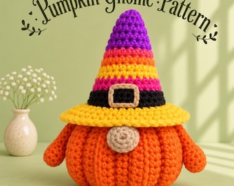 May include: A crocheted pumpkin gnome with a textured orange body, a beige nose, and a tall, pointed hat featuring horizontal stripes of purple, orange, and pink, finished with a black band and a beige buckle. The text Pumpkin Gnome Pattern is visible.