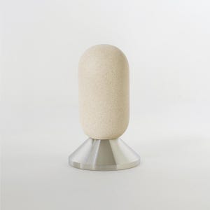 May include: A beige ceramic lamp with a speckled finish and a silver metal base. The lamp has a rounded, cylindrical shape.