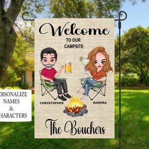Peut inclure: Une pancarte de bienvenue personnalisée pour un camping avec un couple de dessins animés assis autour d'un feu de camp. La pancarte indique "Bienvenue sur notre camping" et porte les noms "Christopher" et "Sandra" sous le couple. Le texte "The Bouchers" est en bas de la pancarte.