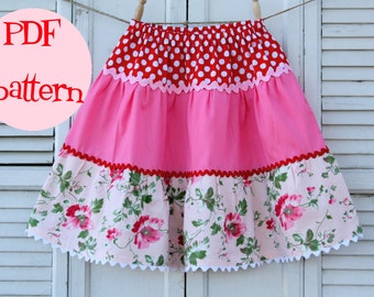 May include: PDF pattern for a tiered skirt with a red and white polka dot top layer, a pink middle layer, and a floral bottom layer. The skirt has white scalloped trim around the bottom.