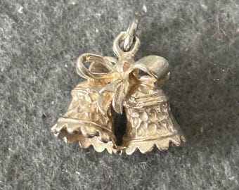 May include: Silver charm featuring two bells tied together with a bow. The bells have a textured surface.