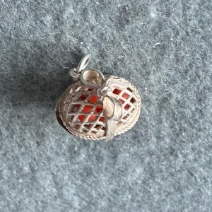 Peut inclure: Pendentif en argent avec un motif en treillis enfermant une sphère orange vif. Le pendentif a une petite boucle en haut pour une chaîne. Le travail du métal détaillé et la couleur vive créent un contraste saisissant.