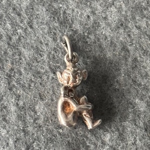 Puede incluir: Encanto de plata de un elfo sentado con un sombrero puntiagudo y una pequeña figura en su regazo.