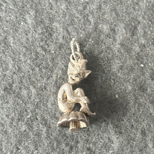 May include: A silver charm of a small, sitting fairy with wings, perched on a mushroom.