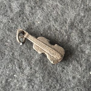 Peut inclure: Un charme en argent en forme de violon. Le charme a une boucle en haut pour l'attacher à un bracelet ou un collier.