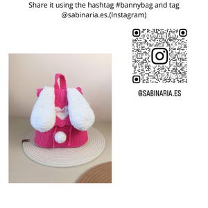 May include: A pink crocheted bunny backpack with white fur ears and a white pom-pom. The backpack is sitting on a woven straw mat. The image includes the text "@SABINARIA.ES" and a QR code.