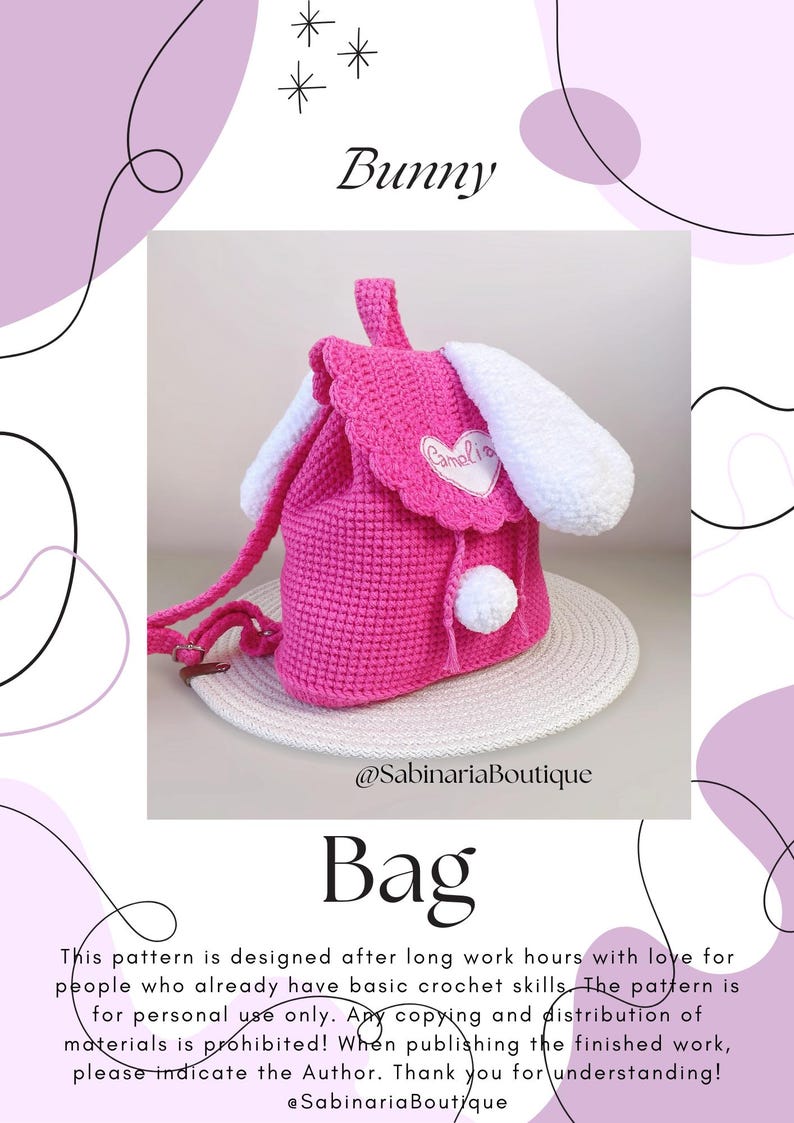 May include: Pink crocheted bunny-shaped bag with white ears and a white pom-pom. The bag has a drawstring closure and a white heart-shaped patch with the name "Camelia" embroidered on it. The bag is sitting on a woven straw mat.  @SabinariaBoutique