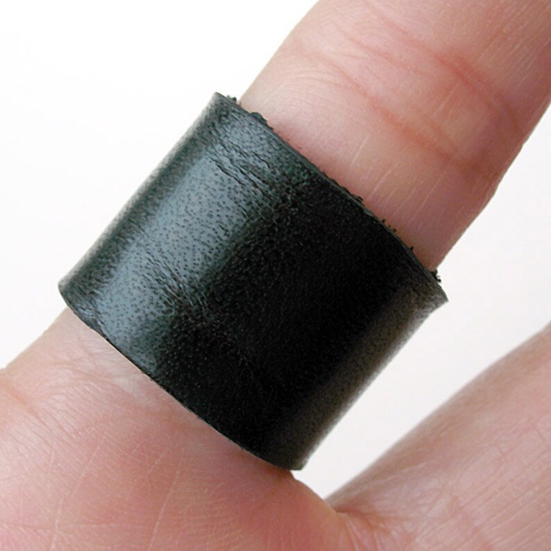 Puede incluir: Un anillo de cuero negro usado en un dedo.