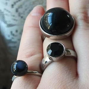 May include: A white ceramic mug with a black handle and the text "But First, Coffee" in a bold, black font. The mug is sitting on a wooden surface. The mug is approximately 4 inches tall.