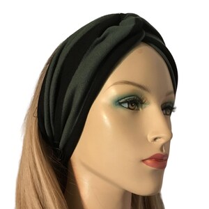 May include: A dark green and black striped headband. The wide, knotted headband is made of a soft, stretchy fabric. The headband is designed to be worn around the head, and is shown on a mannequin with blonde hair.
