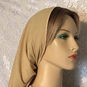 May include: A light brown head scarf made of a soft, stretchy fabric. The scarf is worn on a mannequin with a light brown wig.