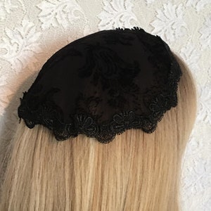 May include: Black lace head covering with a scalloped edge.