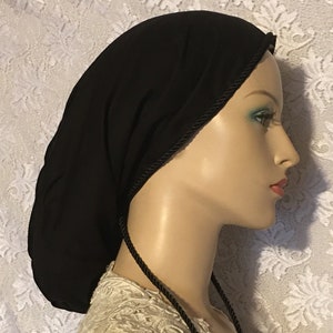 May include: A black fabric sleep cap with a black satin trim and ties. The cap is designed to help keep hair from getting frizzy while sleeping.