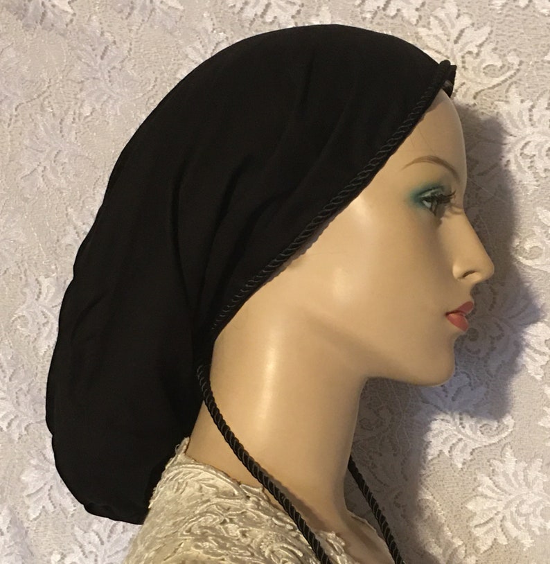 May include: A black fabric sleep cap with a black satin trim and ties. The cap is designed to help keep hair from getting frizzy while sleeping.