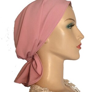 Puede incluir: Un cubrecabezas de tela rosa con un nudo atado en la parte posterior del cuello. El cubrecabezas est&aacute; hecho de un material suave y el&aacute;stico y est&aacute; dise&ntilde;ado para ser c&oacute;modo y elegante.