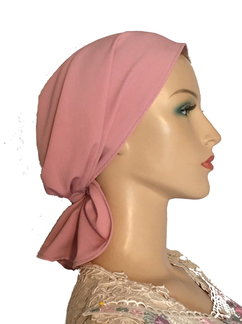Puede incluir: Un cubrecabezas de tela rosa con un nudo atado en la parte posterior del cuello. El cubrecabezas est&aacute; hecho de un material suave y el&aacute;stico y est&aacute; dise&ntilde;ado para ser c&oacute;modo y elegante.