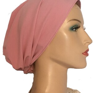 Puede incluir: Un cubrecabezas de estilo turbante de punto de jersey rosa. La tela es suave y el&aacute;stica.