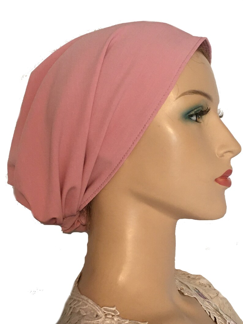 Puede incluir: Un cubrecabezas de estilo turbante de punto de jersey rosa. La tela es suave y el&aacute;stica.