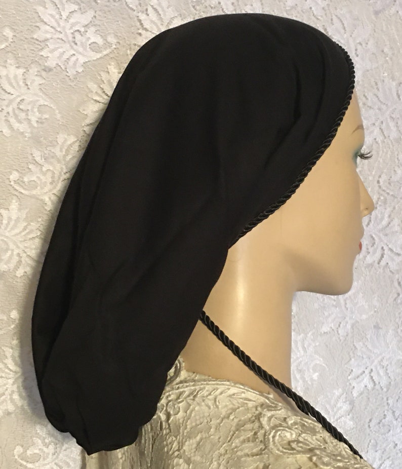 May include: Black satin sleep cap with a black satin drawstring and black trim. The cap is worn on a mannequin head.