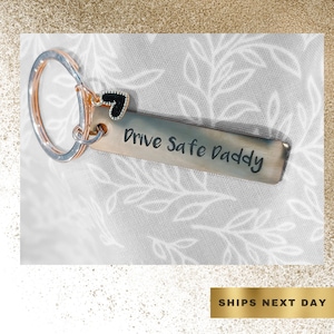 May include: A silver key chain with a black heart charm and a silver tag that says "Drive Safe Daddy".