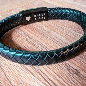 Personalized Black Leather Bracelet for Men – Engraved Magnetic Clasp | Custom Gift for Husband, Boyfriend or Dad, Custom Father's Day name. Whether you're engraving your kids' names, an anniversary date, or a private message tucked discreetly inside, this bracelet brings sentimental value to a piece he’ll actually want to wear. A black leather bracelet with a braided design and a silver clasp. The clasp has a heart engraved on it and the text '2.10.97 7.16.24'.