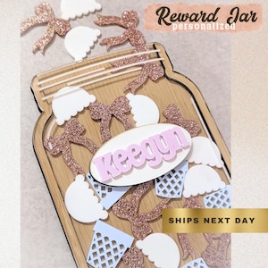 May include: A wooden reward jar with a personalized name, decorated with glittery bows, white cloud shapes, and light blue ice cream cones. The text "Reward Jar personalized" is at the top.
