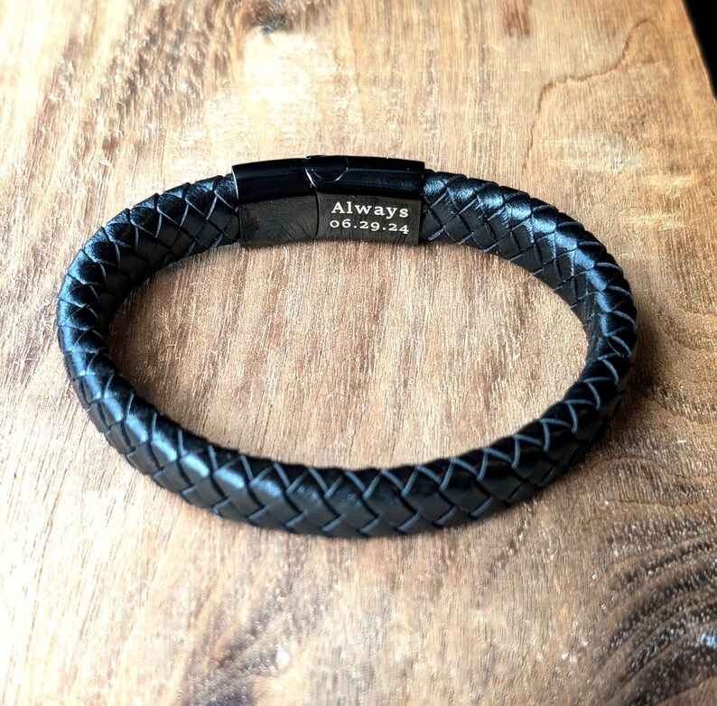 Personalized Black Leather Bracelet for Men, Engraved Magnetic Clasp | Custom Gift for Husband, Boyfriend or Dad, Custom Father's Day name. Handcrafted from black braided leather with an engraved black clasp, this personalized bracelet is rugged, refined, and ridiculously handsome. Black braided leather bracelet with a engraved black metal plate that reads “Always 06.29.24.” Displayed on a rustic wooden surface, this personalized accessory makes a meaningful anniversary or wedding gift for him